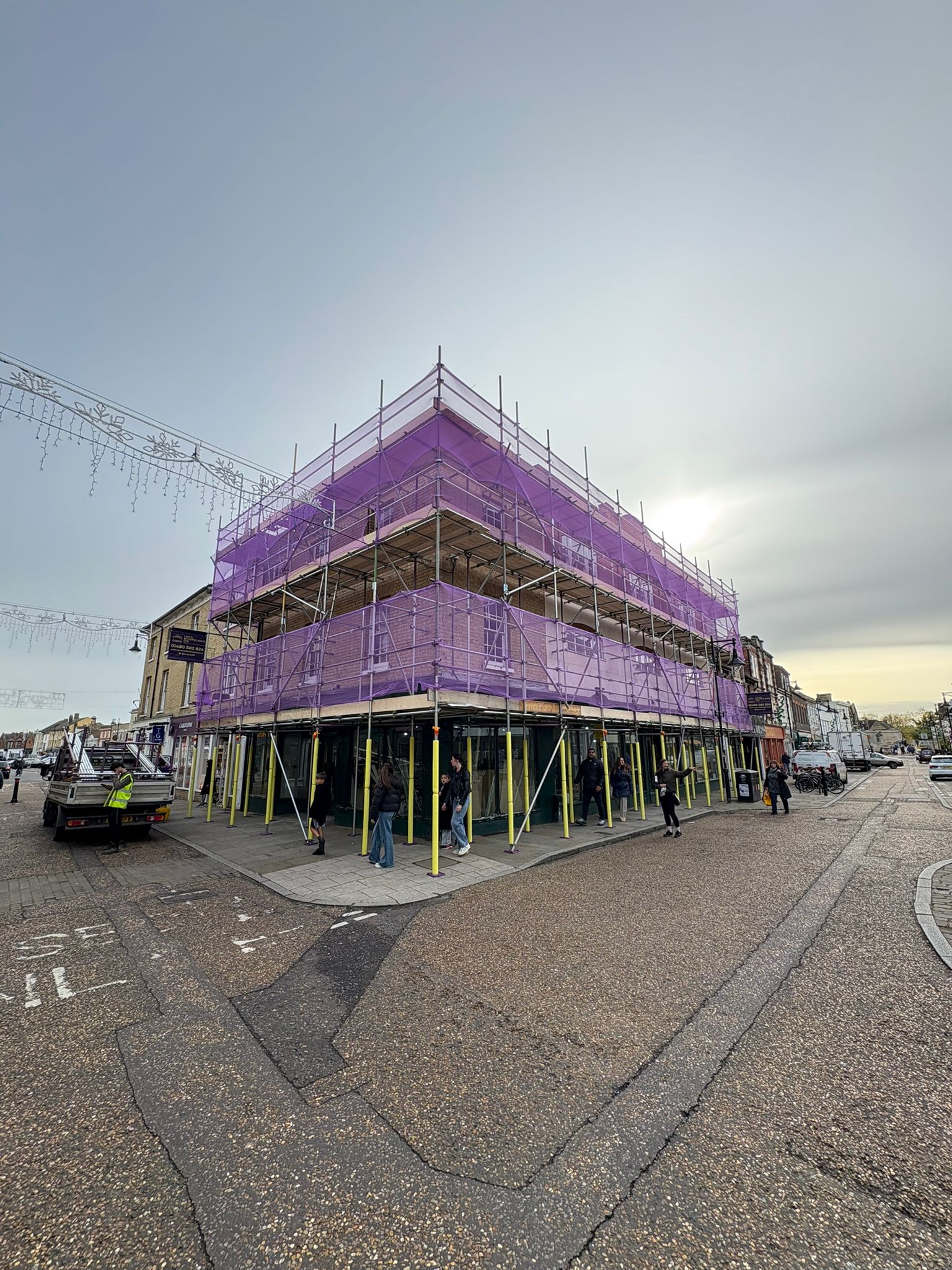 Commercial scaffold with purple debris netting wrapping a three-storey period property on a town high street